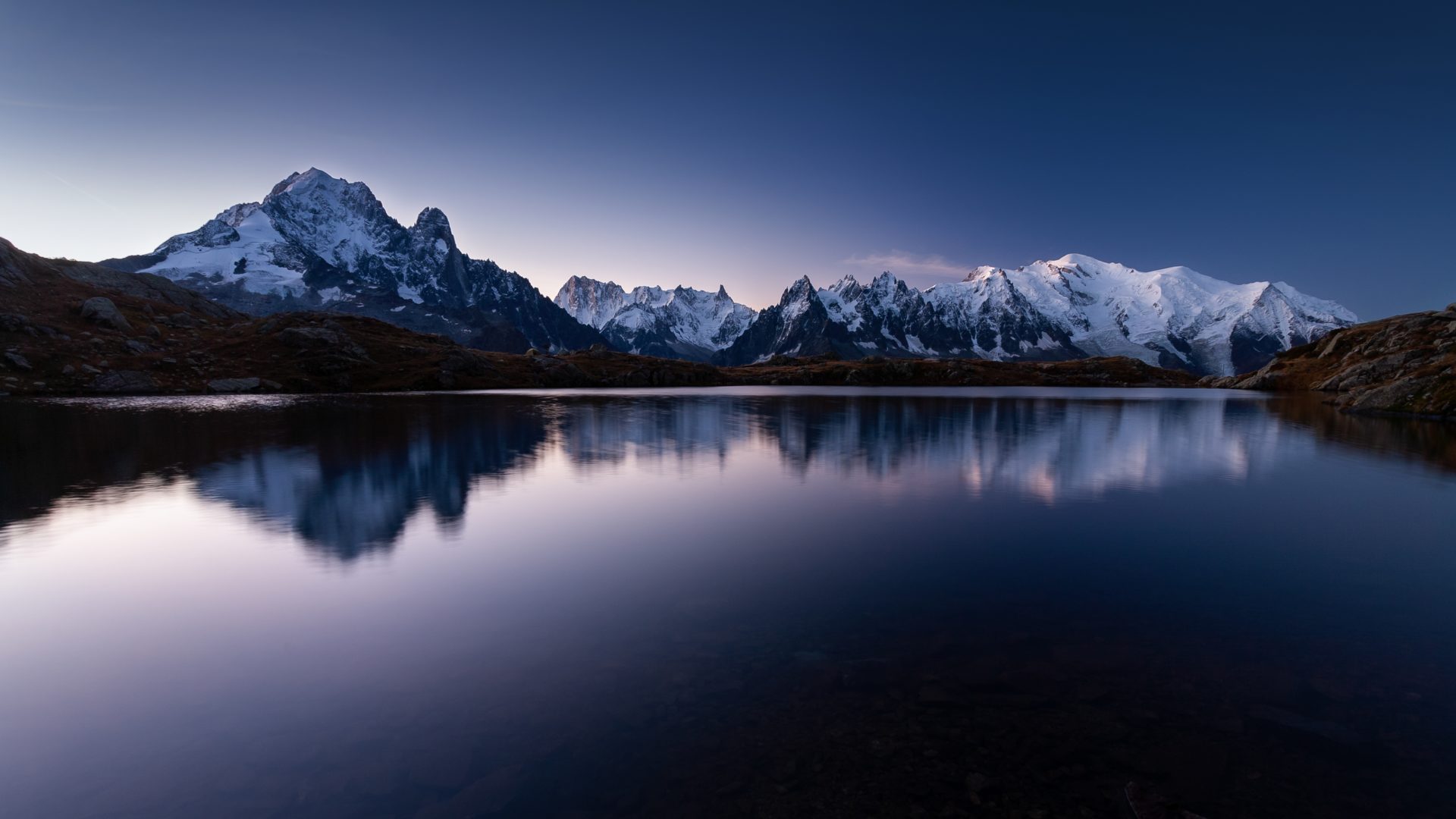 The mount Mont Blanc covered in the snow reflecting on the water in the evening in Chamonix, France